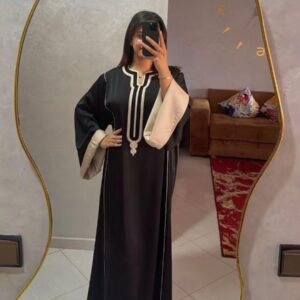 Caftan Sofia noir avec revers crème porté devant un miroir